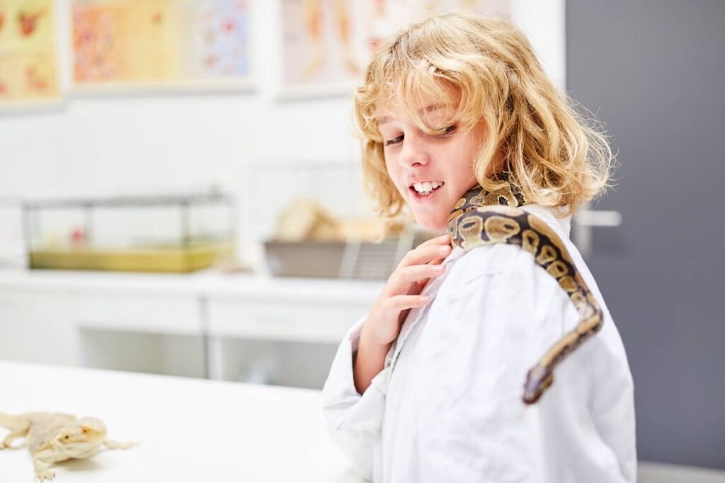 Dete drži zmiju na ramenu